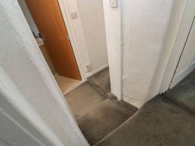 A hallway with carpet and doors leading to other rooms at The Cottage in Budleigh Salterton
