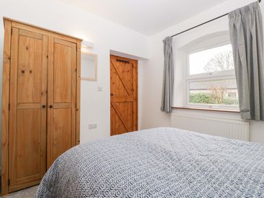 A bedroom with a wardrobe, door, window, and radiator at Castle Rag in Lydney