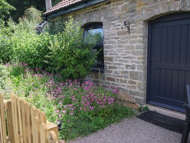 An outdoor area with flowers and a wooden gate at Castle Rag in Parkend
