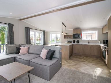 A living room with a sofa and kitchenette at Tulip in Eardisland