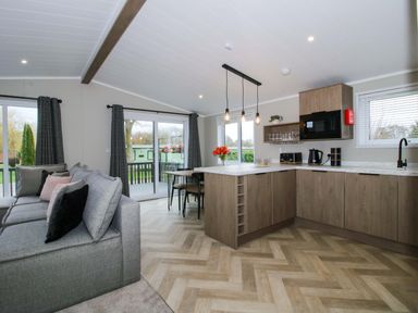 A living room with a sofa and kitchen area at Poppy in Eardisland