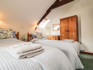 A bedroom with two beds and wooden furniture at Applestore in Wadebridge