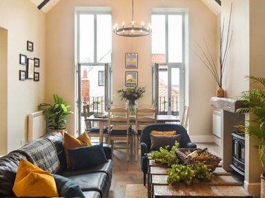 A living room with a dining area and windows at Juniper Cottage
