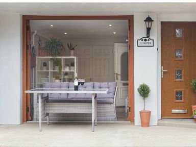 An outdoor seating area with a couch, table, and plants at Juniper Cottage
