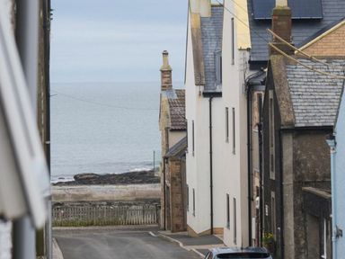 A coastal view with buildings along the road near the sea at Juniper Cottage