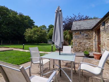 An outdoor seating area with a table and chairs at Little Trethellan in Trethellan near Lanner