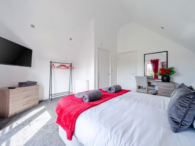 A bedroom with a bed, TV and dresser at Ruby Red Near Brigg