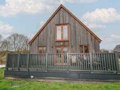 A house with a deck and windows at Pumpkin Lodge in Brigg