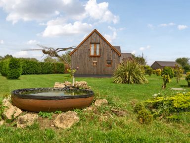 A garden with a water feature and a house in the background at Pumpkin Lodge near Brigg