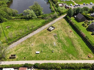 An outdoor area with a swing set and storage unit near a body of water at Pumpkin Lodge near Brigg