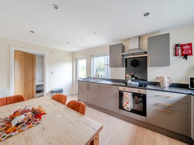 A kitchen with cabinets and a dining table at Lodge 25 - Pumpkin Near Brigg