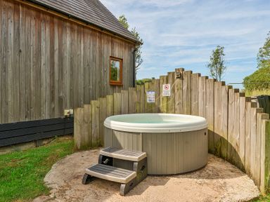 An outdoor area with a hot tub and wooden fence at Poker Lodge Near Brigg