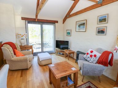 A living room with a sofa, table, and tv at Casa Mia in Goodwick