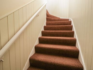 A staircase with carpet and a handrail at Cottage No 9 in Keswick