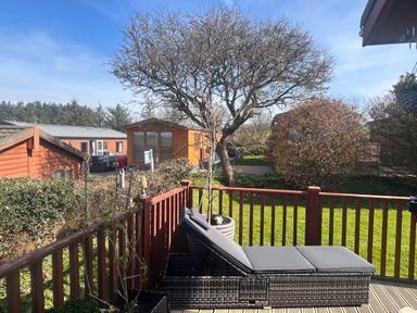 An outdoor patio with a lounge chair and trees at 1 Ocean Terrace Mullacott near Ilfracombe