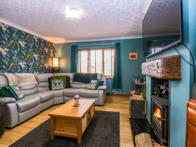 A living room with a sofa, coffee table and fireplace at 36 Cae Rhos in Holyhead