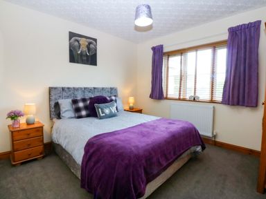 A bedroom with a bed and nightstands at 36 Cae Rhos in Holyhead
