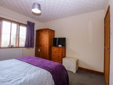 A bedroom with a bed, wardrobe, television and chest of drawers at 36 Cae Rhos in Holyhead
