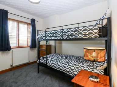 A bedroom with a bunk bed and lamp at 36 Cae Rhos in Holyhead