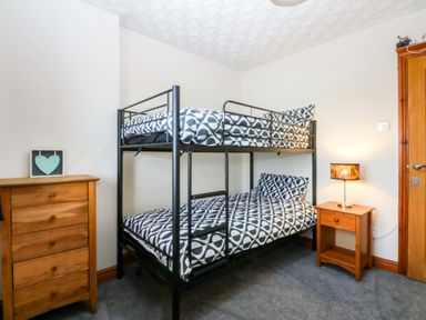 A bedroom with a bunk bed and a wooden chest of drawers at 36 Cae Rhos in Holyhead