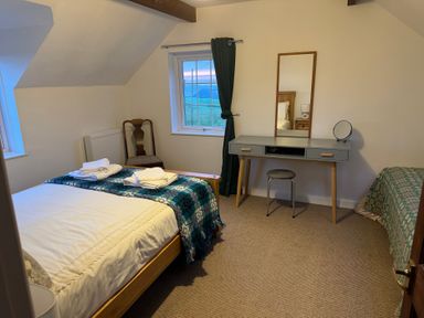 A bedroom with a bed, desk, and window at Penpegws near Aberystwyth