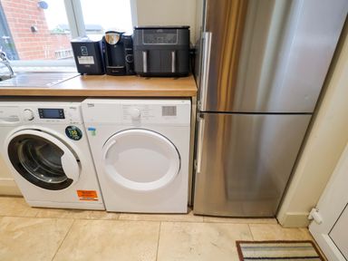 A kitchen with a washing machine and dryer next to a refrigerator at Cliff Cottage