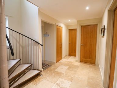 A hallway with a staircase and multiple doors at Cliff Cottage