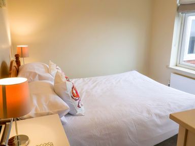 A bedroom with a bed and bedside table at Cliff Cottage