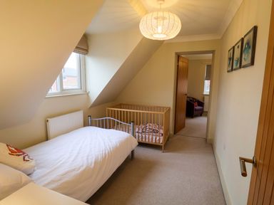 A bedroom with a bed and crib at Cliff Cottage