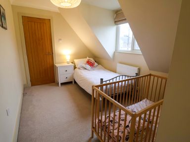 A bedroom with a bed and a crib at Cliff Cottage