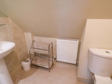 A bathroom with a wash basin, toilet, towel rack and radiator at Cliff Cottage