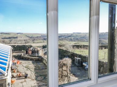 A view from a window overlooking hills and a terrace at Dove Cottage in Hexham