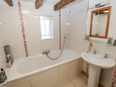 A bathtub and sink with a mirror in the bathroom at Dove Cottage in Hexham