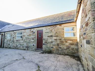 An outdoor area with stone walls and a door at Swallows Rest in Hexham