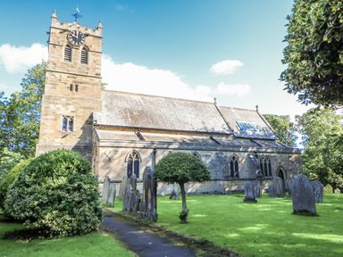 A church with a clock and grave stones in the yard at Swallows Rest Hexham