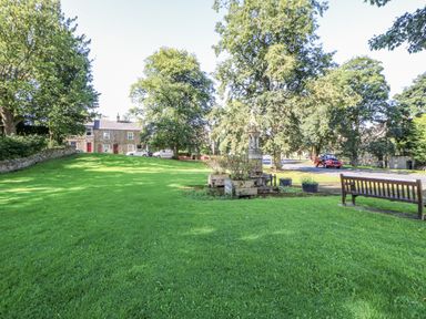 A park with grass trees and a bench at Swallows Rest in Hexham