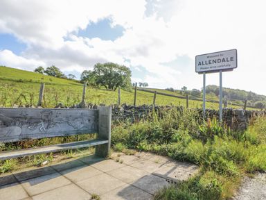 A sign welcoming to Allendale and a bench along the roadside in Allendale