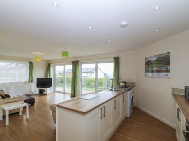 A living room with a kitchen area and a view of the outside at Orme View in Penmaenmawr