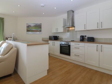 A kitchen with cabinets, stove, and appliances at Orme View in Penmaenmawr