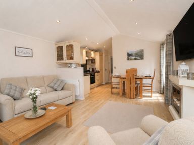 A living room with a sofa and dining area at Tiggywinkle Beck - White Cross Bay Windermere