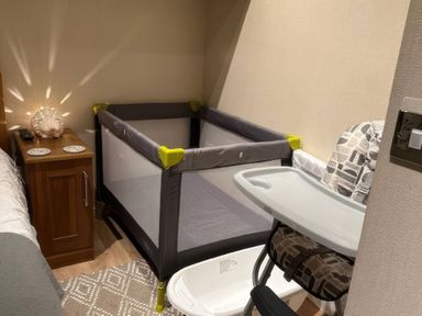 A bedroom with a crib and a chair at Tiggywinkle Beck - White Cross Bay Windermere
