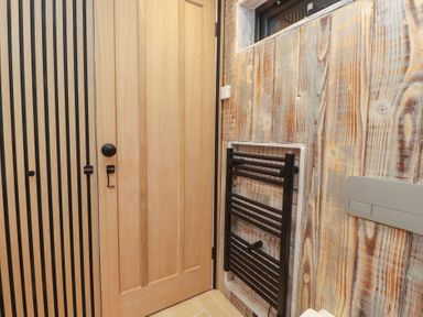 A bathroom with a door and a heating rail at Riverside Lodge Afonwen
