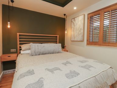 A bedroom with a bed and wall art at Riverside Lodge Afonwen