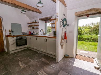 A kitchen with cupboards and a view to the outside at Rhos Y Clegyrn Goodwick
