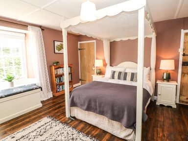 A bedroom with a canopy bed and bookshelf at Englewood Cottage in Hexham
