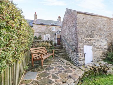 A garden with a bench and stone steps at Englewood Cottage in Hexham