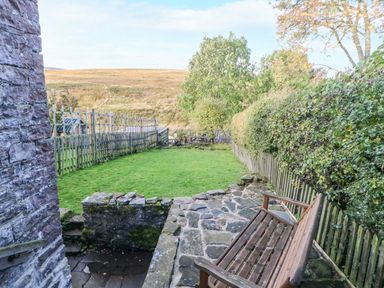 A garden with a wooden bench and stone pathway at Englewood Cottage in Hexham