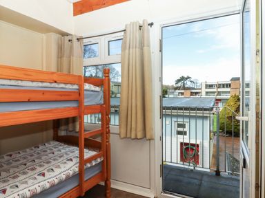A bedroom with a bunk bed and a window leading to a balcony at Flat 1 Lee Cliff Park in Dawlish Warren