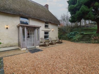 A house with a thatched roof and chairs in front at Plenteth Truro