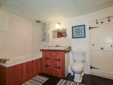 A bathroom with a bathtub, toilet, sink, and mirror at Plenteth in Truro